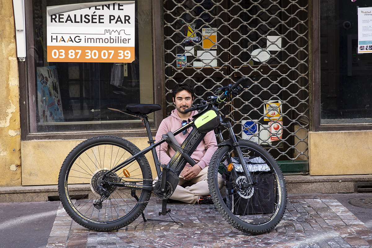 Cykelbuden har ingenstans att ta vägen mellan körningarna. Zabihullah Ahmadi sitter på en kartongbit utanför en nedlagd butik och väntar på nästa jobb. Foto: Anna Trenning-Himmelsbach