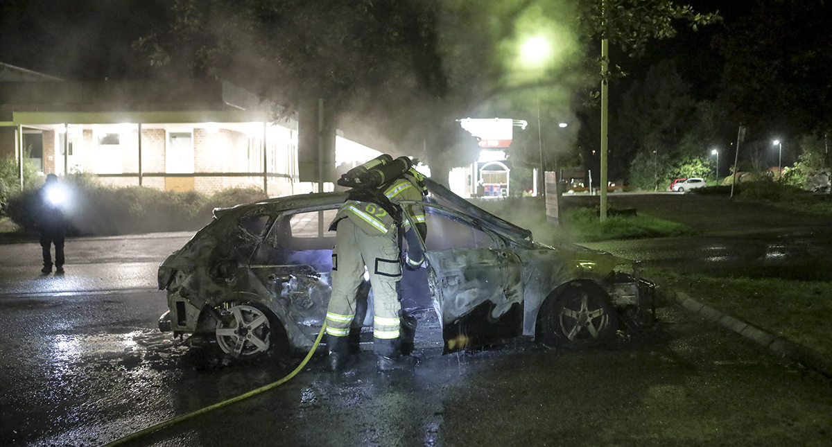 Trollhättan 2017 09 14 Sylts center En av två utbrända bilar efter upplopp på Sylte Brandman som släcker.