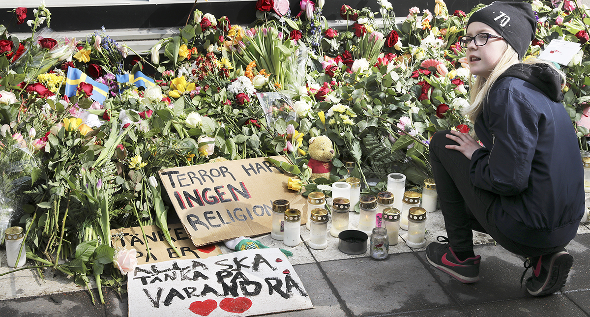 Flicka vid blomsterhav efter terrorattacken på Drottninggatan