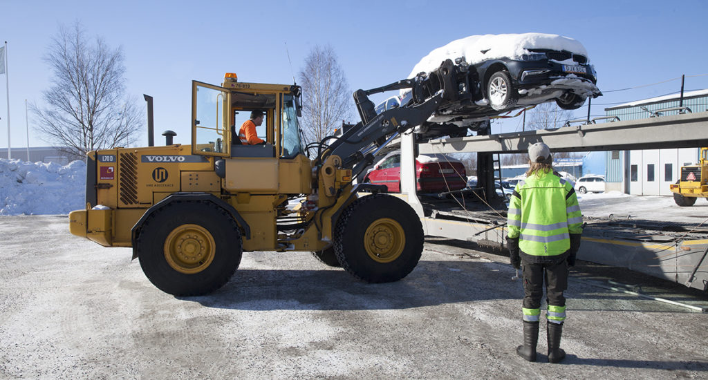 Ume Assistance. Jörgen Björk tar hjullastaren och lyfter upp kraschade bilar på en biltransporttrailer som ska flytta dem till skroten.