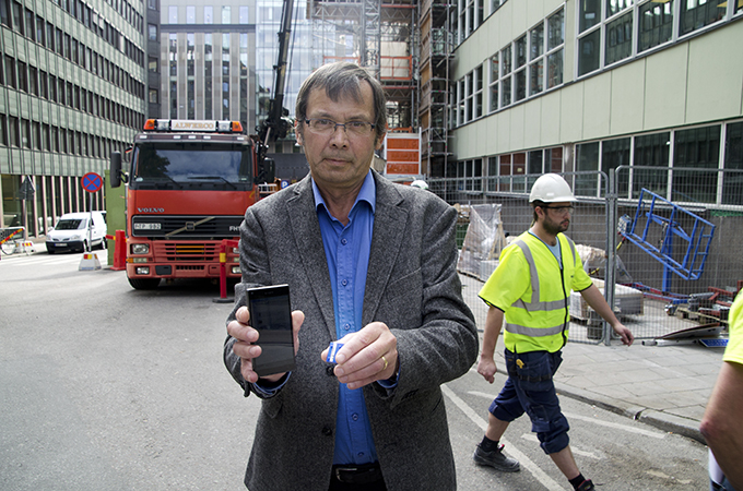 Pensionerade forskaren Lage Burström vid Umeå universitet visar upp vibrationsmätaren som kan kopplas till en mobilapp och larma om skakningarna blir höga och hälsofarliga. Värdena kan också överföras till och analyseras på datorn. Foto: Roland Cox