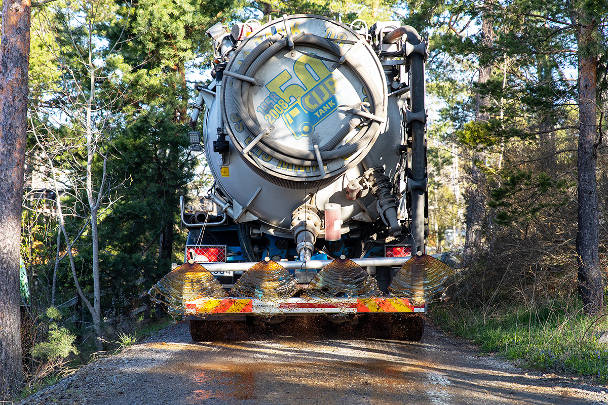 Slambilschauffören Jimmy Söderström sprider ”brunsås”, Dustex, på vägarna i ett tomtområde på Ingarö. ”Dustex är melodin nu, en restprodukt från trävaruhanteringen som består av kåda och vatten. Den binder vägdamm och är bättre för miljön än salt”, förklarar Jimmy.