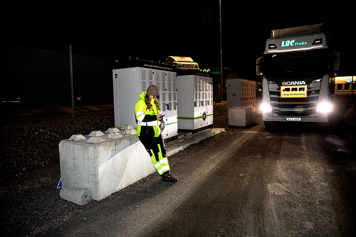 Lastbilschauffören Mimmi Broström väntar på att hennes långa fordonståg ska ladda färdigt i ett ödsligt industriområde. Foto: Justina Öster