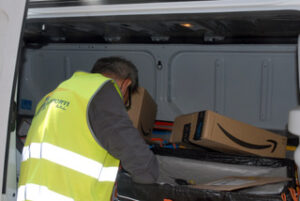 En man i gul varselväst packar paket. 