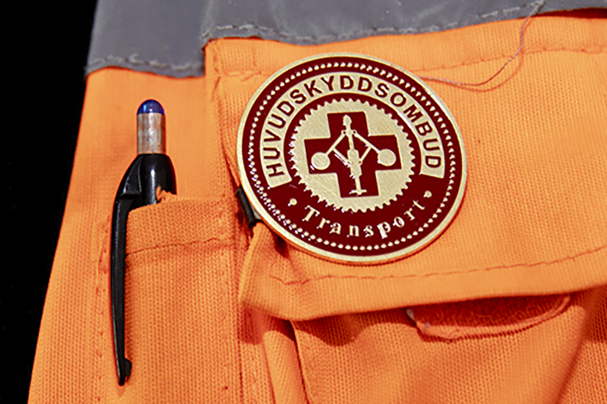 Huvudskyddsombudsmärke på orange varseljacka