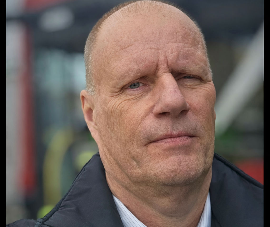 En skallig man som kisar och ser bestämd ut.